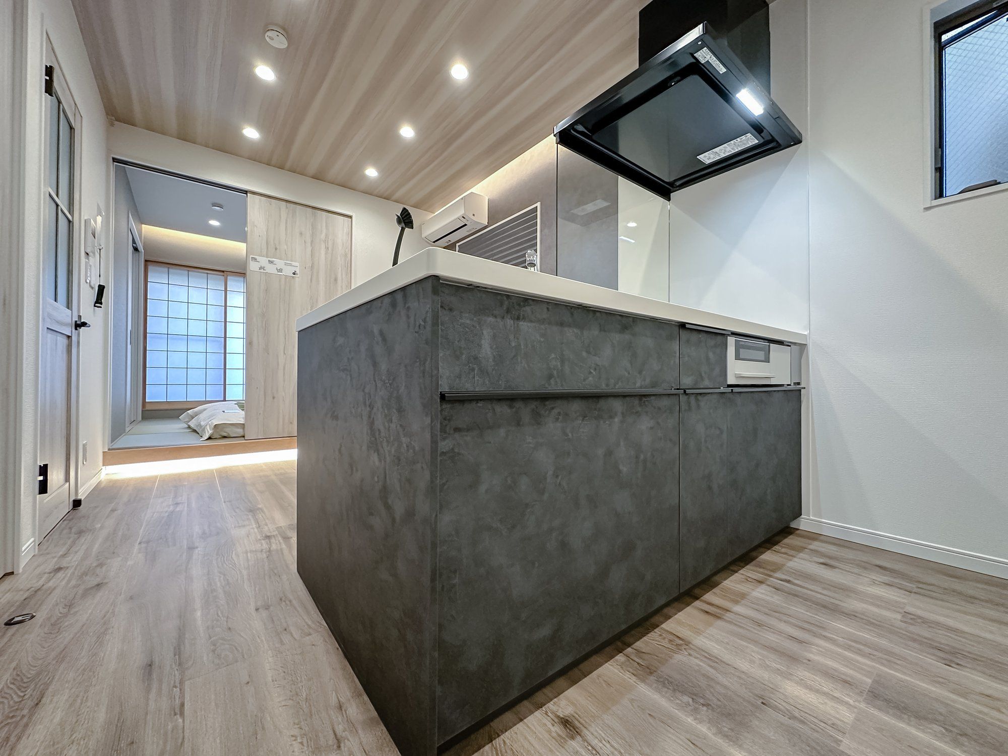 A modern kitchen with a built-in island, recessed ceiling lights, and a large window.