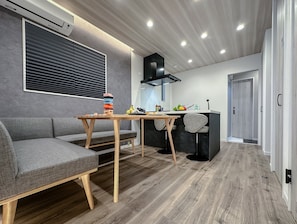 A modern kitchen with a dining area, a built-in stove, and a window with blinds. - HANASTAY KIWAMI (Osaka)