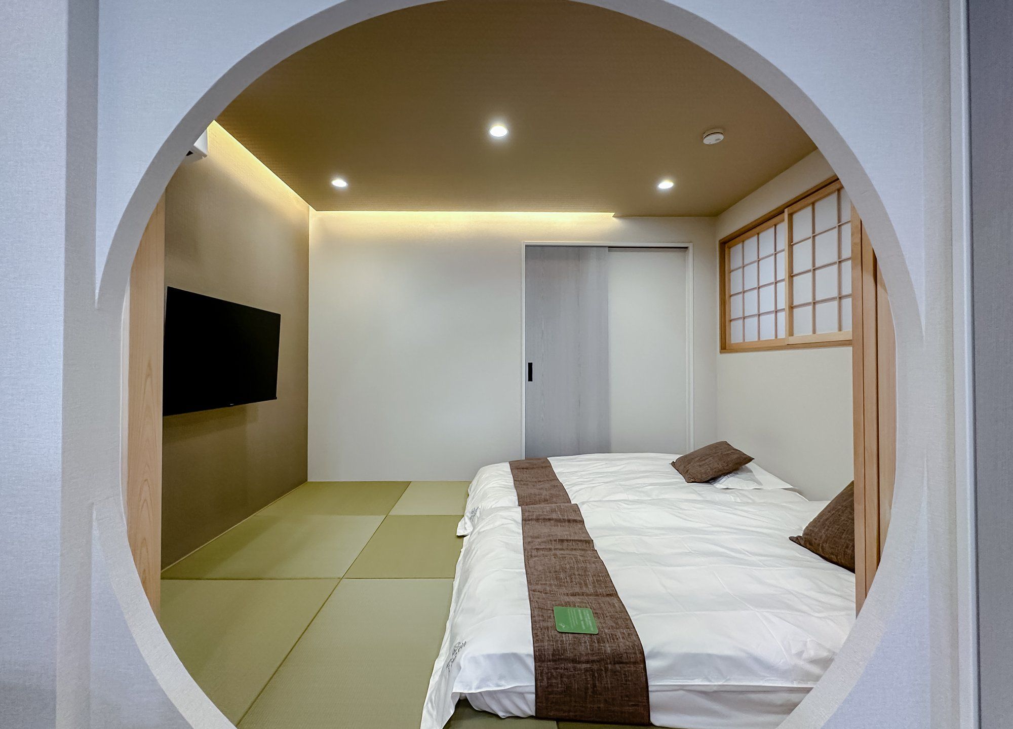 A circular room with a bed, a television on the wall, and a sliding door.