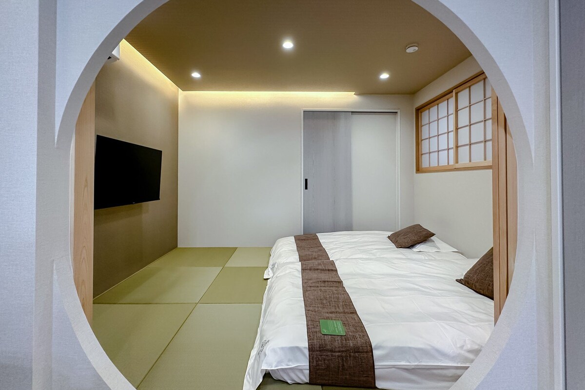 A circular room with a bed, a television on the wall, and a sliding door.