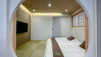 A circular room with a bed, a television on the wall, and a sliding door.