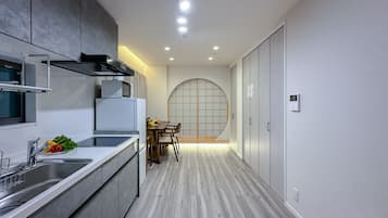 A modern kitchen with a built-in microwave, a refrigerator, and a sink. There is a dining area with a table and chairs.