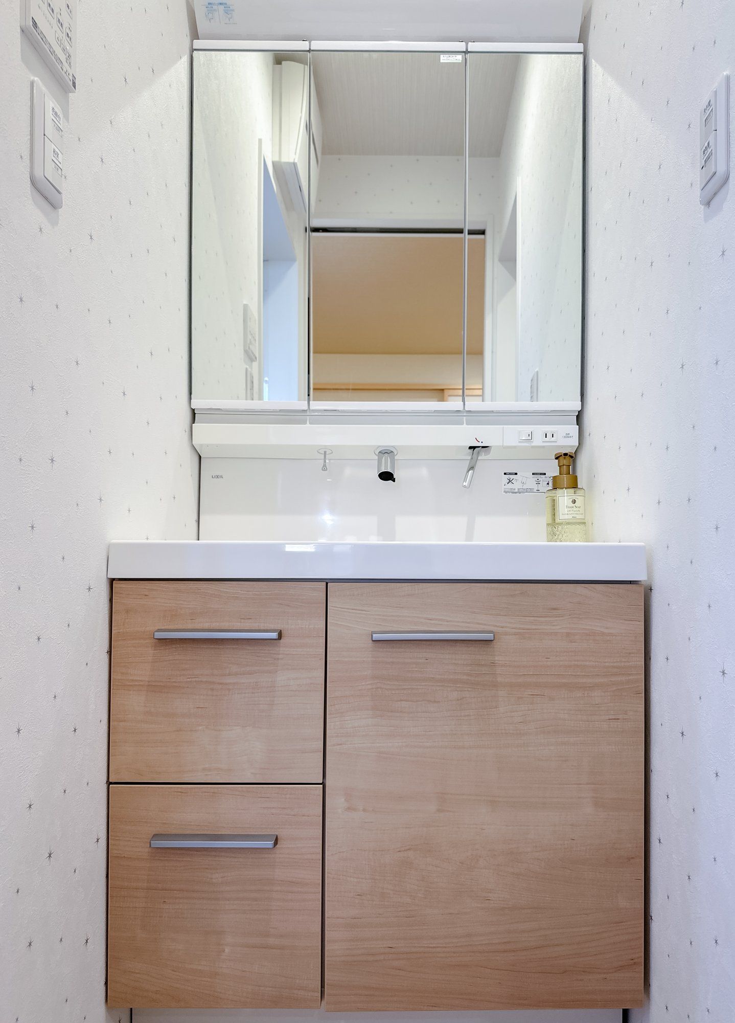 A bathroom with a white sink, a mirror above it, and wooden cabinets below.