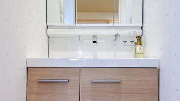 A bathroom with a white sink, a mirror above it, and wooden cabinets below.
