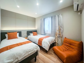A hotel room with two beds, a wooden ladder, and a single orange chair. - HANASTAY KIWAMI (Osaka)