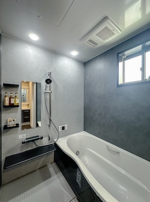 A modern bathroom with a bathtub, a shower, and a vanity with a mirror. - HANASTAY KIWAMI (Osaka)