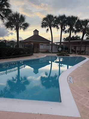 A swimming pool surrounded by palm trees and a building with a sign. - Cozy Private Studio, 20 Minutes from Disney (Clermont)