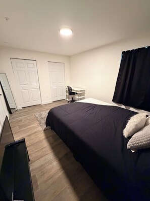 A bedroom with a bed, a desk, and two doors. - 1br Apartment in ATL (Atlanta)