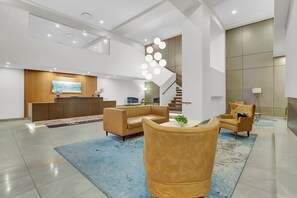 A modern lobby with a reception desk, sofas, a staircase, and a decorative light fixture. - PremiumStays: Cozy 1-bed loft apt in Playhouse Sq : Theater : Sports : Parking (Cleveland)