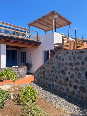 A modern building with a stone wall, wooden deck, and a covered outdoor area.
