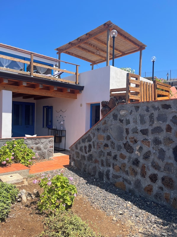 A modern building with a stone wall, wooden deck, and a covered outdoor area.
