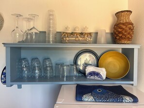 A shelf with glassware, decorative items, and a woven basket.