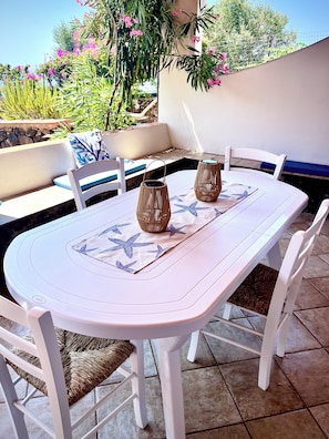 An outdoor patio with a white table and chairs, two wicker lanterns, and a blue and white patterned table runner.