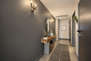 A modern hallway with a wooden console table, a mirror, and a patterned rug. - The Bentley Collection - The Turquoise Loft (Dallas)