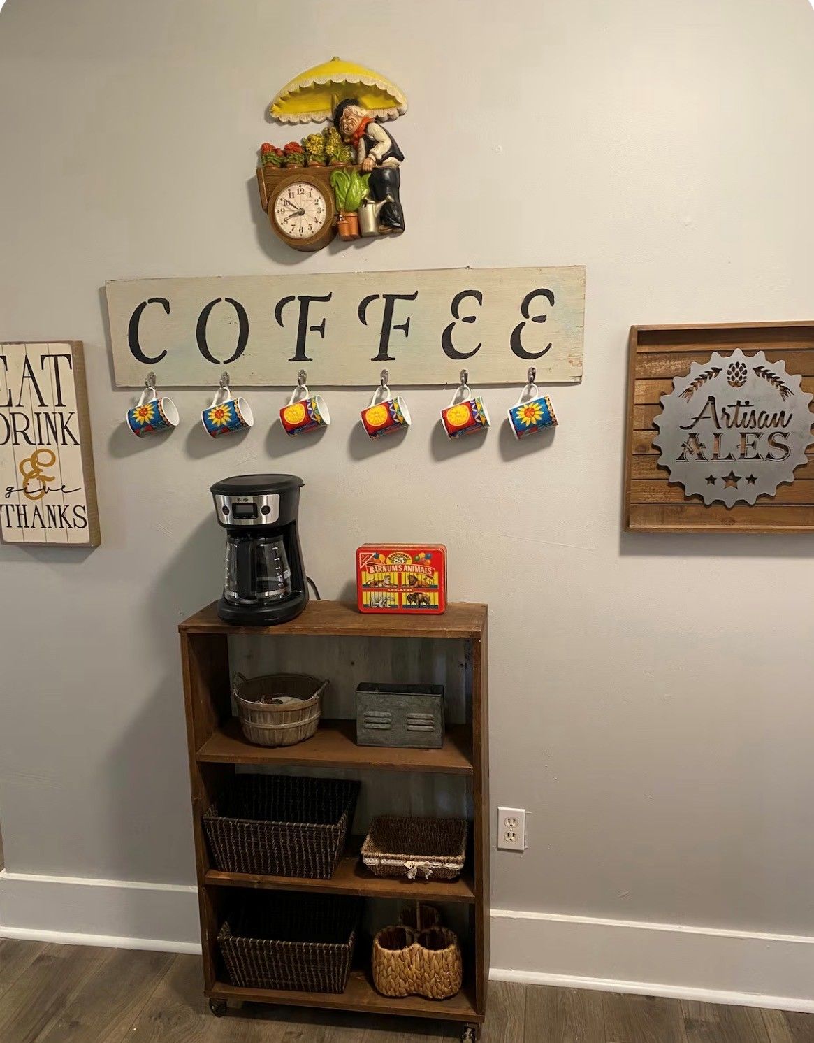 A wall with a coffee-themed decoration, a coffee maker, and a shelf with baskets.