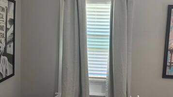Un dormitorio con ventana, radiador, cama y un cuadro en la pared.