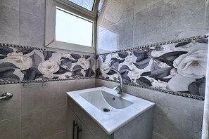 A bathroom with a sink, a window, and floral patterned tiles. - Soul OF Pyramids Golf Epic view (Giza Governorate)