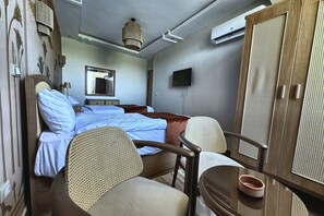 A hotel room with a bed, a chair, a wardrobe, a television, and a ceiling light. - Soul OF Pyramids Golf Epic view (Giza Governorate)