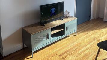 A room with a television on a wooden cabinet, a framed picture on the wall, and a door with a lock.