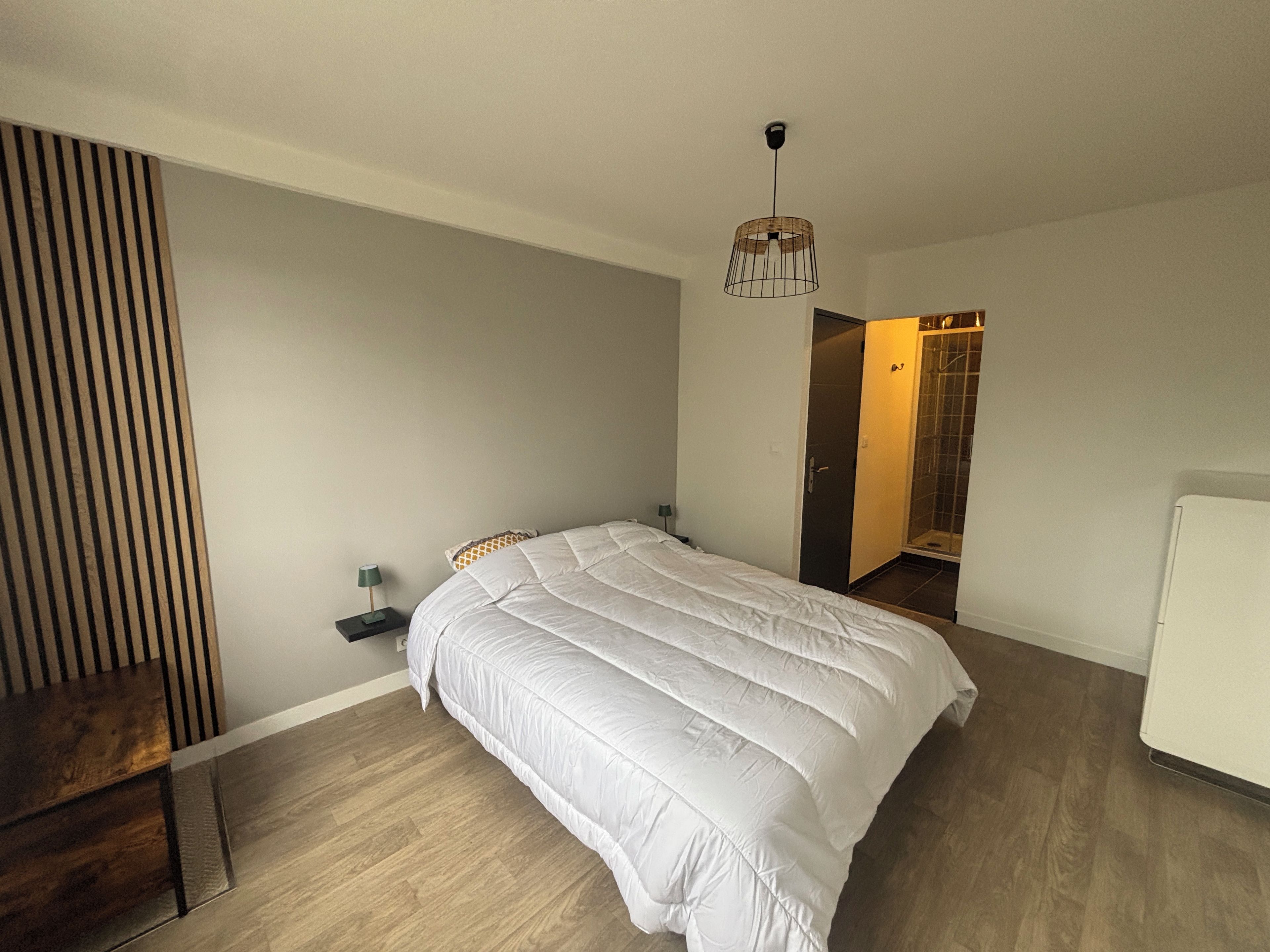 Ein Schlafzimmer mit einem Bett, Nachttischen, einem Kleiderschrank und einem Duschbereich.