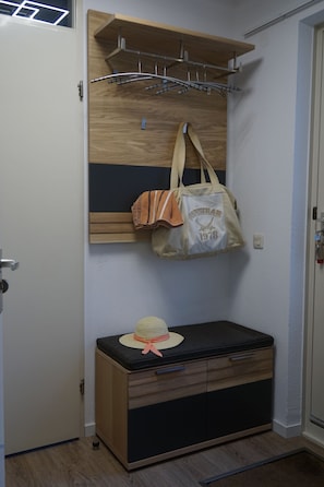 Ein Zimmer mit einem Holzkabinett, einer aufhängbaren Tasche und einem Hut auf dem Kabinett.