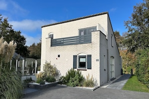 Ein modernes, zweistöckiges Gebäude mit Ziegelaußenwand, einem kleinen Vorgarten und blauem Himmel.