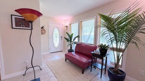 Un salon avec un canapé rouge, une plante en pot et un lampadaire.