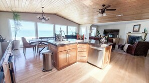 Une cuisine spacieuse dotée d’un grand îlot central, de meubles en bois et offrant une vue sur l’océan.