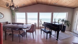 En matplats med ett piano, stora fönster med utsikt över havet och en vacker havsutsikt.