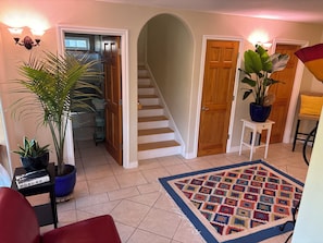 Ein Flur mit Treppe, einem Blumentopf, einem Teppich und einer Tür.