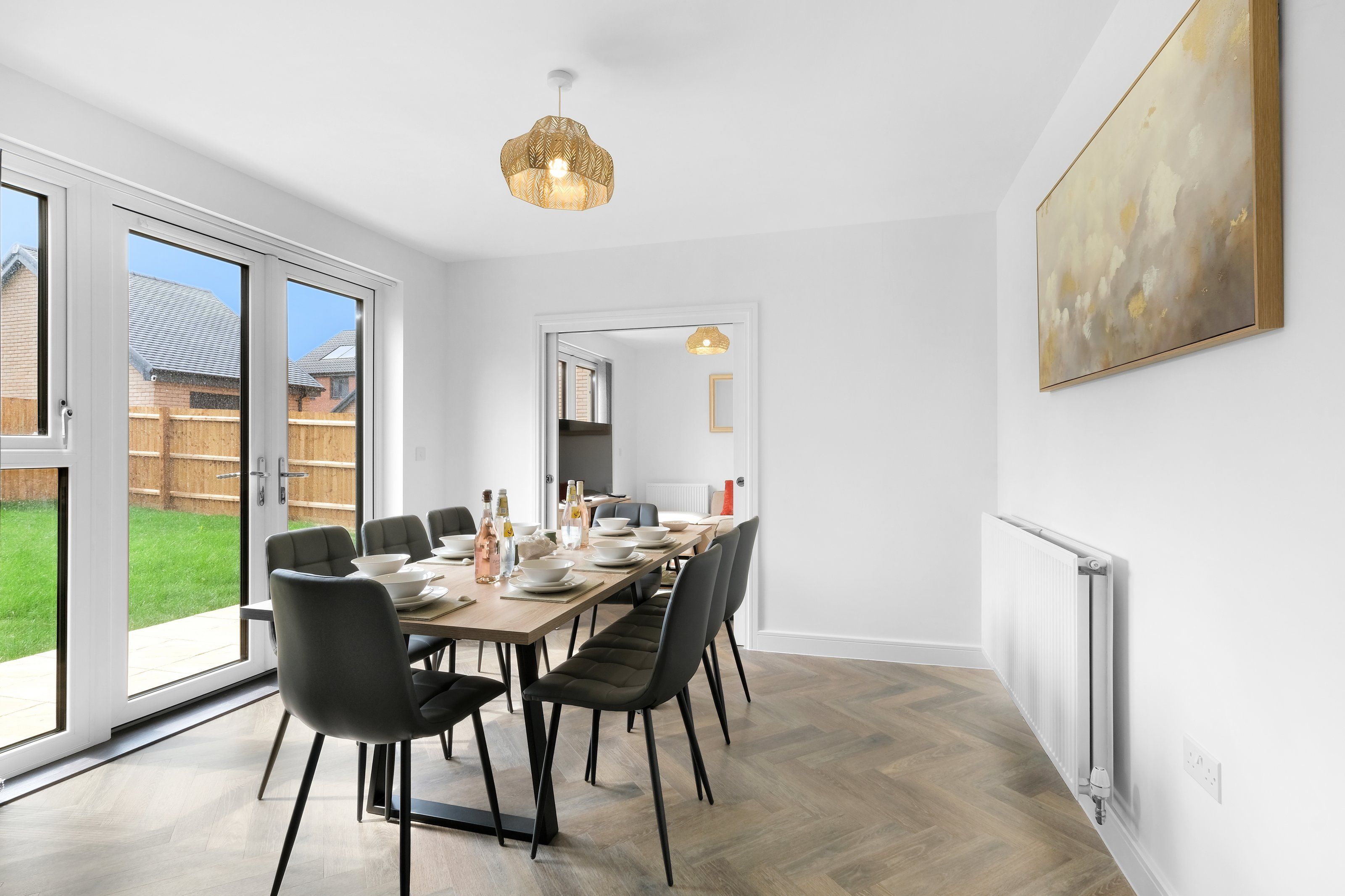 A modern dining area with a long table, chairs, and a pendant light.