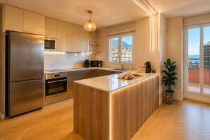 A modern kitchen with stainless steel appliances, a wooden island, and a view of the city. - Monaco Luxury Apartment • Terrace • Parking • Sleeps 5. View of Monaco (Beausoleil)