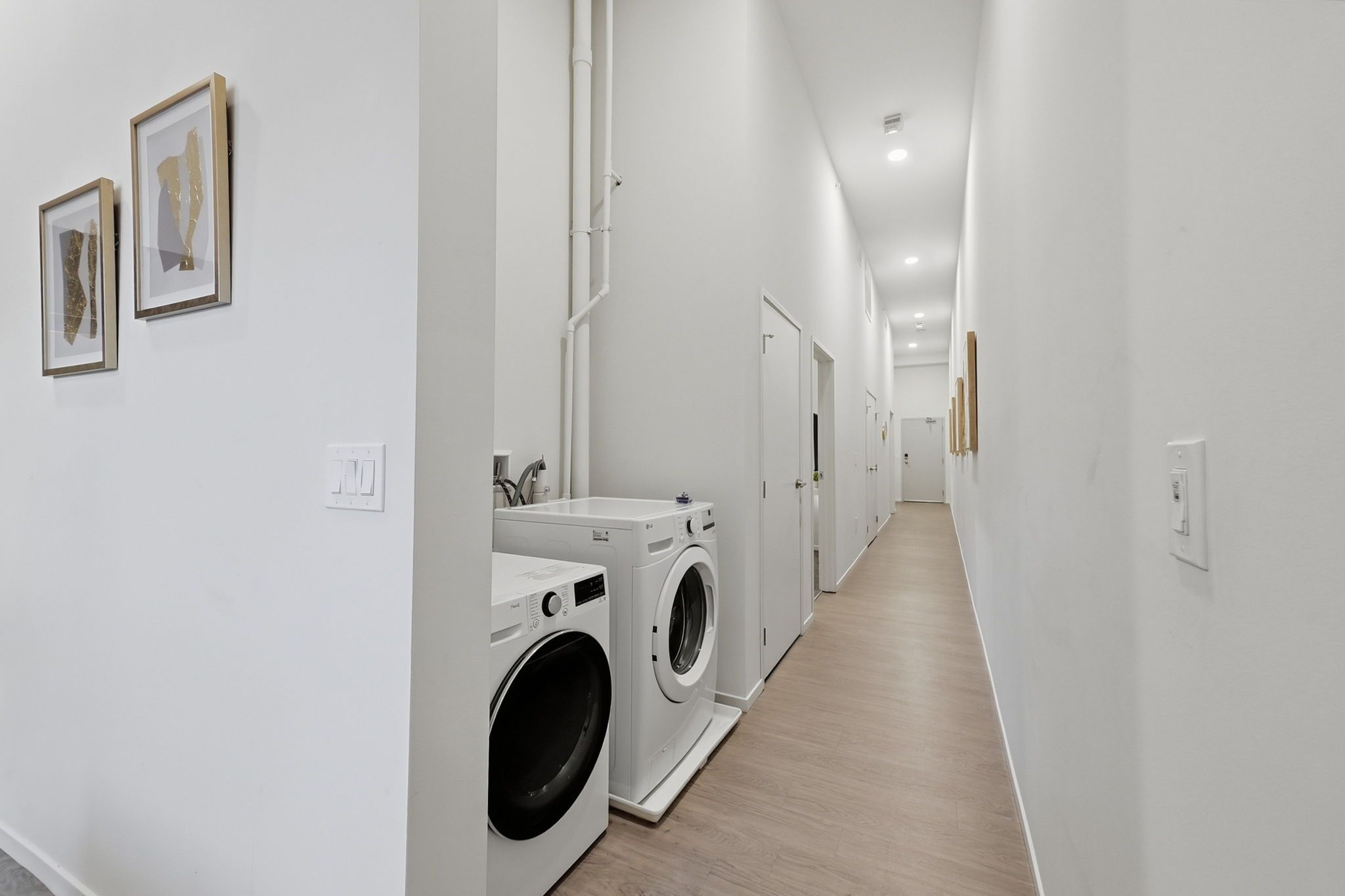 Un lavadero con lavadora y secadora, un lavamanos y una puerta que da a otra habitación.