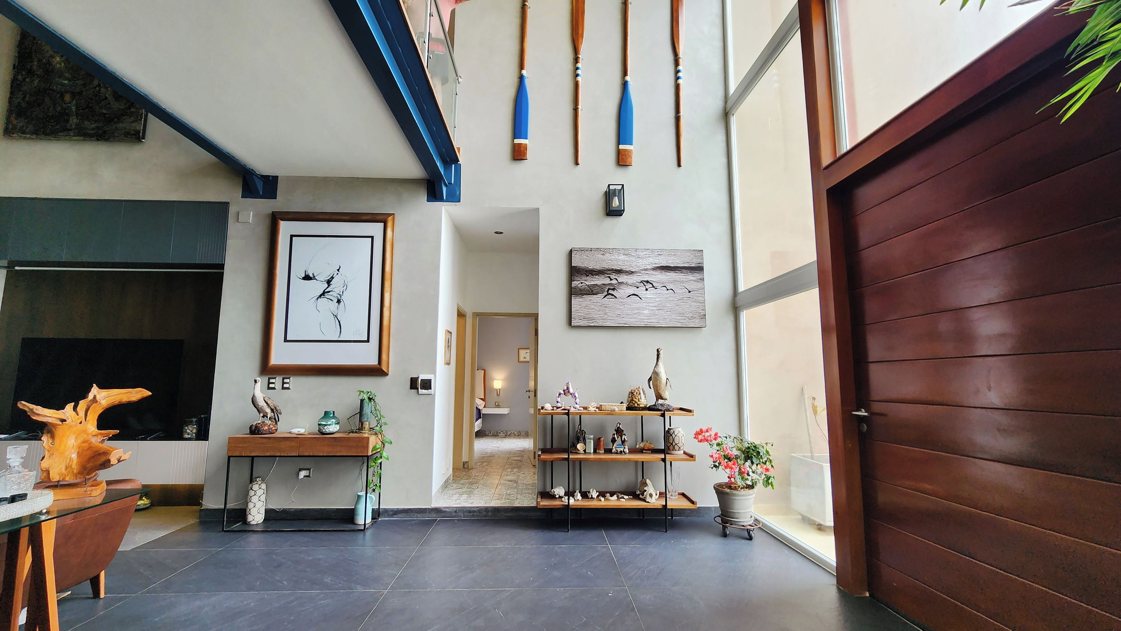 Un intérieur moderne avec un plancher en bois, une cheminée, un tableau abstrait encadré et une porte en bois.