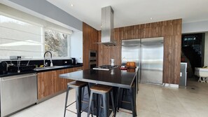 A modern kitchen with a central island, stainless steel appliances, and wooden accents.