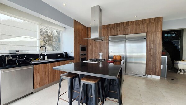 A modern kitchen with a central island, stainless steel appliances, and wooden accents.
