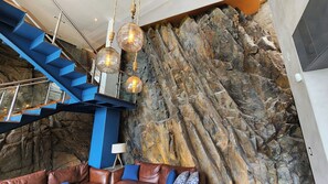 A modern interior with a staircase, a rock wall, and a leather sofa.