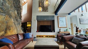 A spacious living area with leather sofas, a flat-screen TV, and a stone accent wall.