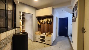 A hallway with a wooden cabinet, a black trash bin, and a blue door.