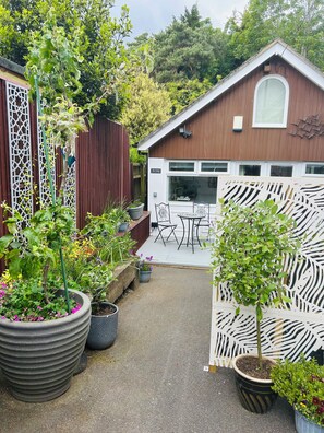 Una casa de fusta amb un patí, plantes en testos i zona de menjador.