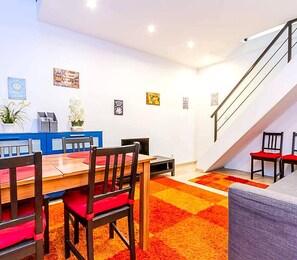 A dining area with a wooden table and chairs, a staircase, and a blue counter. - Fantastic 2-bedroom apartment in the heart of vibrant Budapest. (Budapest)