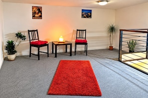 A room with a grey carpet, two chairs with red cushions, a small table with a lamp, and two potted plants. - Fantastic 2-bedroom apartment in the heart of vibrant Budapest. (Budapest)