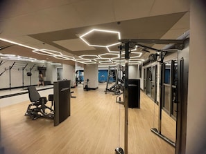 A gym with exercise equipment, a mirror, and a person working out. - Brooklin New Style | Complete, Carrefour 24h and Brooklin Metro, Swimming Pool and Gym (São Paulo)
