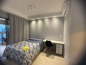 A bedroom with a bed, a desk, a chair, and an air conditioning unit. - Brooklin New Style | Complete, Carrefour 24h and Brooklin Metro, Swimming Pool and Gym (São Paulo)