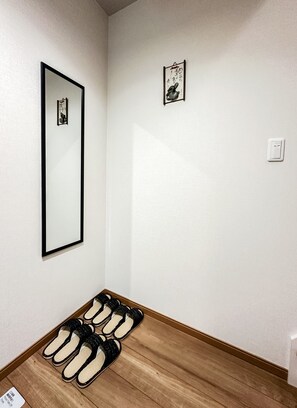 A room with a wooden floor, a black-framed mirror, and a small framed picture on the wall. - HANASTAY TSUMUGI (Osaka)