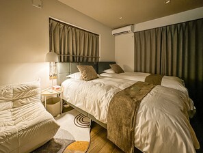 A hotel room with a bed, bedside table, lamp, and a window with curtains. - HANASTAY TSUMUGI (Osaka)