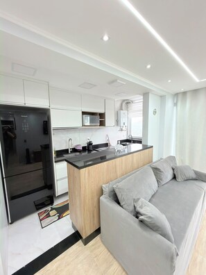 A modern kitchen with a built-in island, a refrigerator, and a microwave. - Feet in the sand via ferry (Rio de Janeiro)