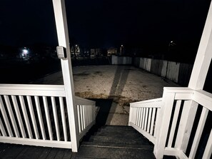 En træterrasse med gelænder, der fører ned til et sandområde.