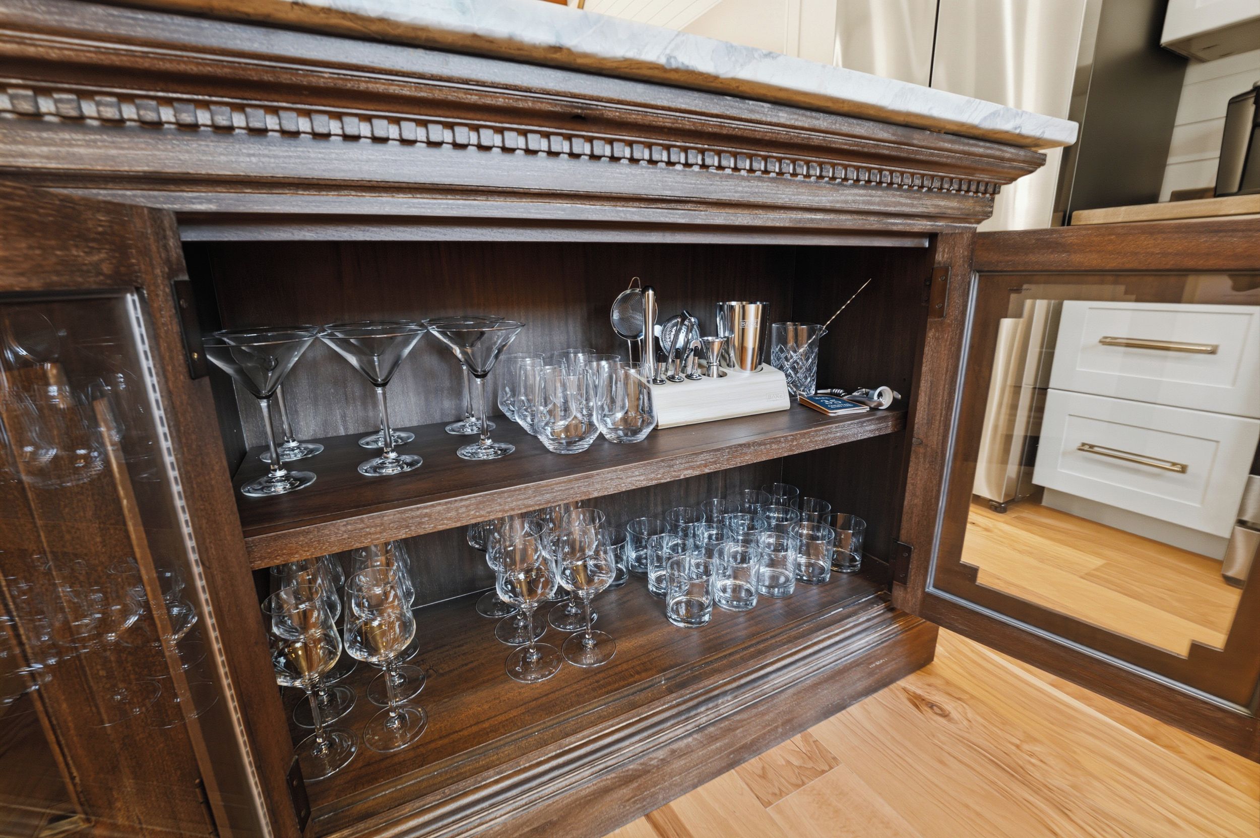 Un mueble de madera con estantes que contienen diferentes tipos de cristalería y una zona de bar.
