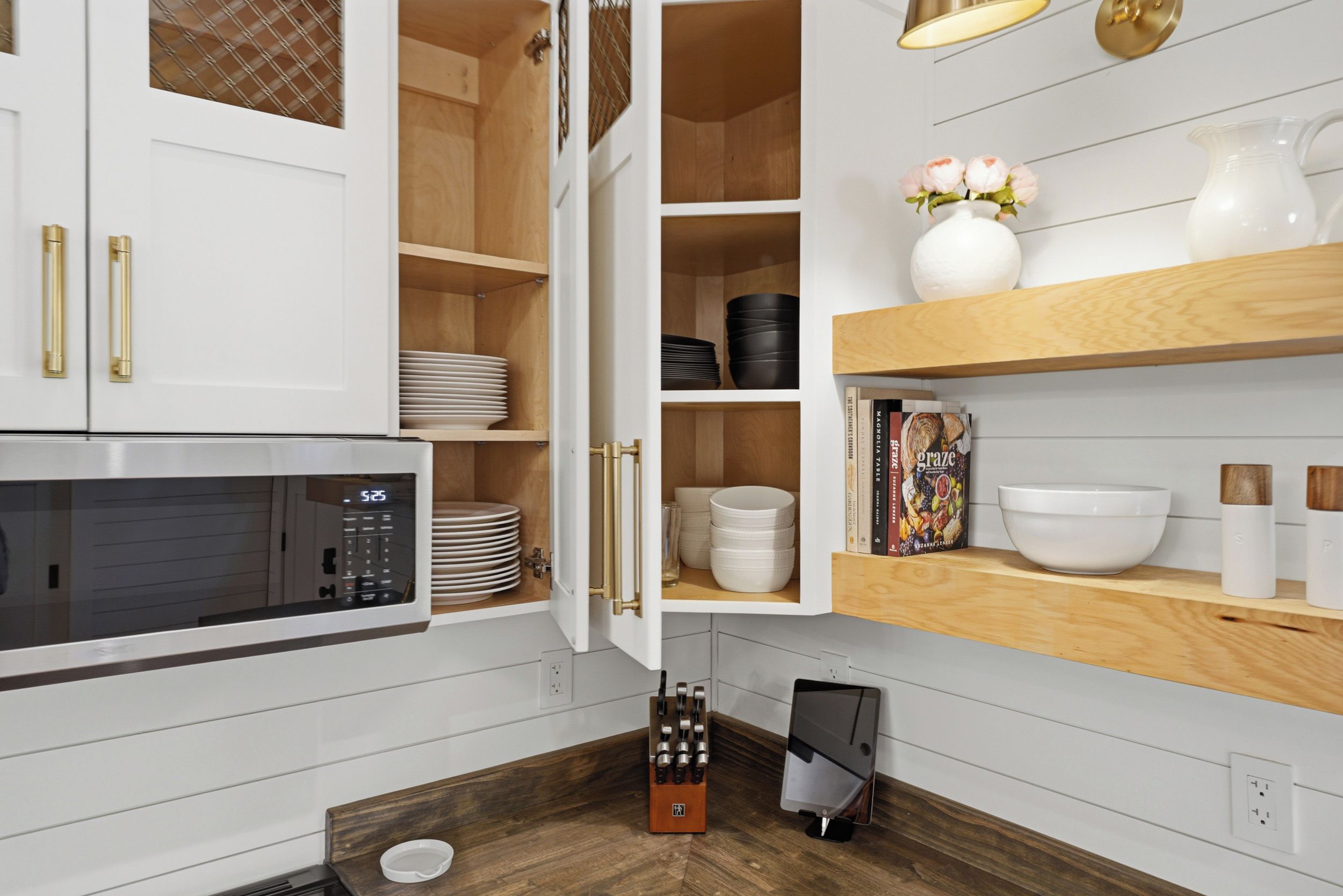 A kitchen with white cabinetry, a microwave, and various kitchenware.